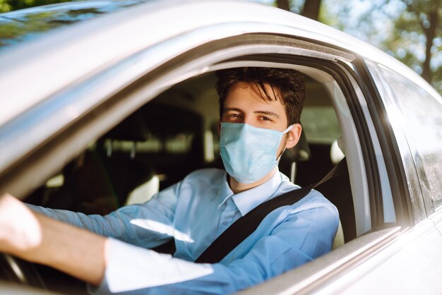 Young man in a protective mask sitting in the car