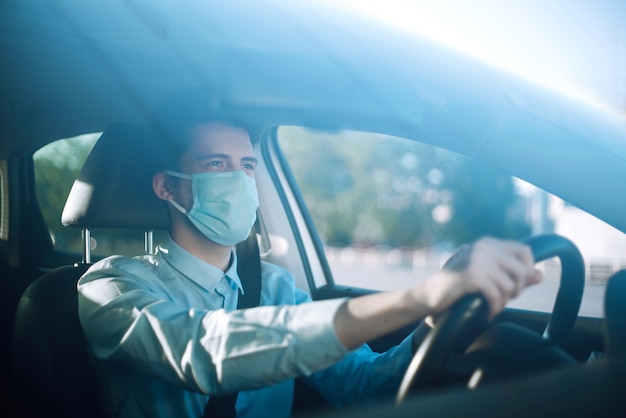 Young man in a protective mask sitting in the car