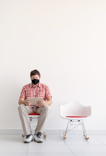 Young man in protective mask studying online keeping social distance