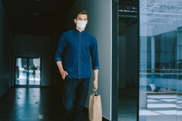 Giovane uomo in una maschera protettiva che cammina lungo una strada cittadina. coronavirus in città