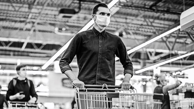 young man in a protective mask with a shopping cart