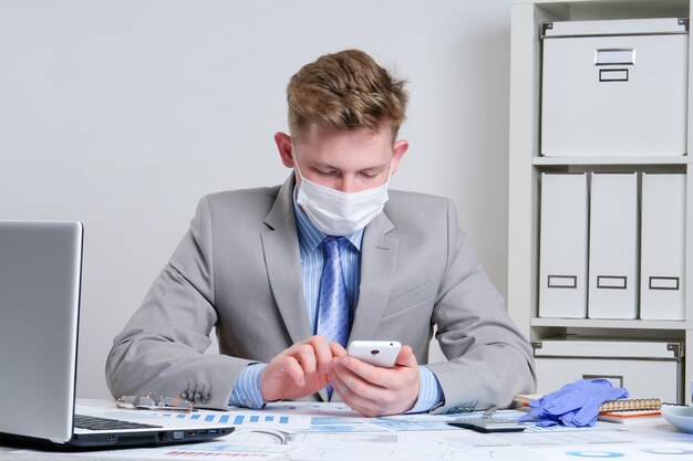 Young man in protective mask working at his desk