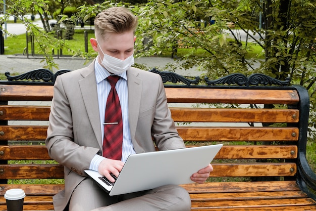 Young man in a protective mask working on a laptop