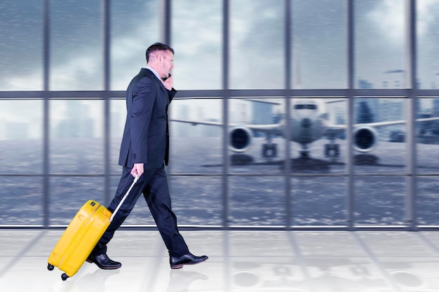 young man pulling suitcase in modern airport terminal travelling guy or businessman concept