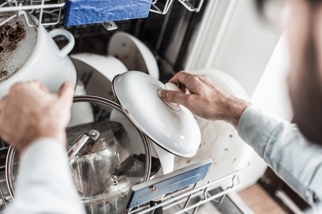 Young man pulls the dishes out of the dishwasher