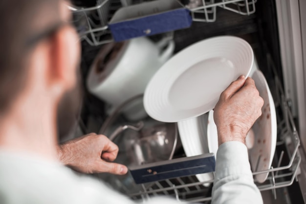 Young man pulls the dishes out of the dishwasher