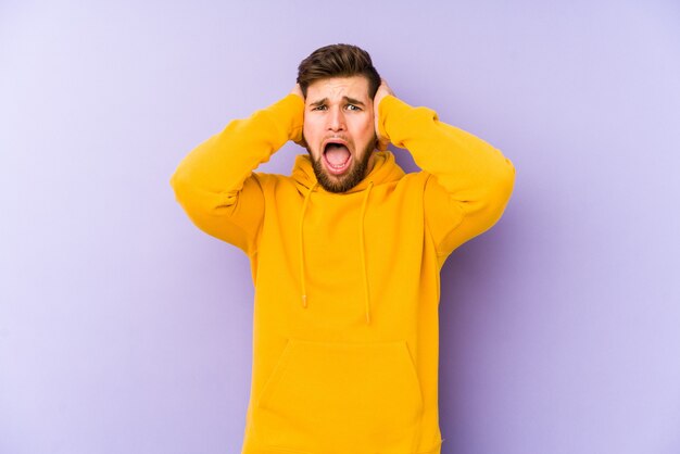 Young man on purple screaming with rage.