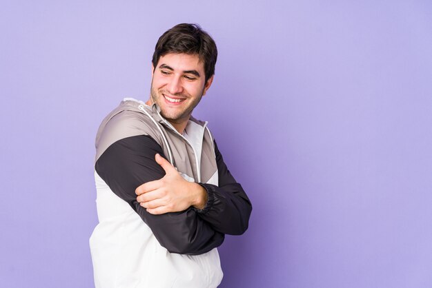 Young man on purple wall laughing and having fun.