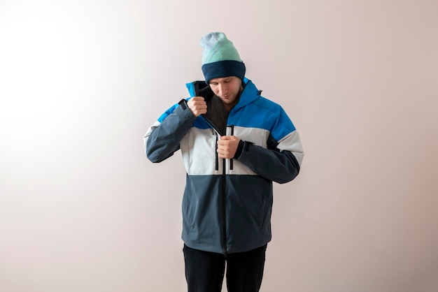 A young man put on winter snowboard jacket warm clothes dressing