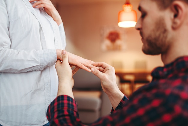 Young man puts the wedding ring on the finger of the beloved.