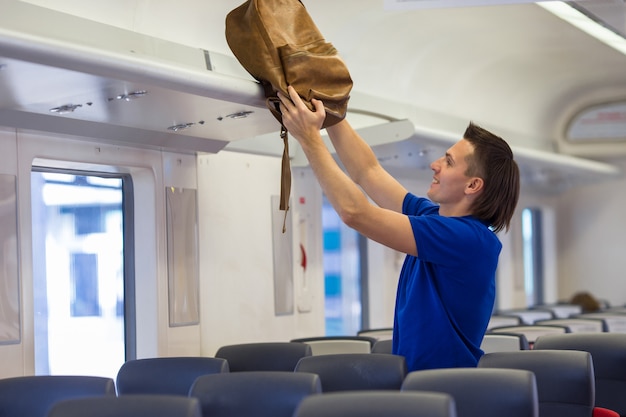 Young man putting luggage into overhead locker at airplane