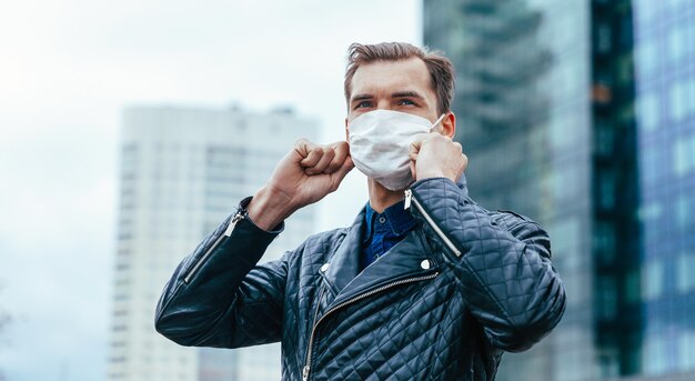 Young man putting on a protective mask standing on the street