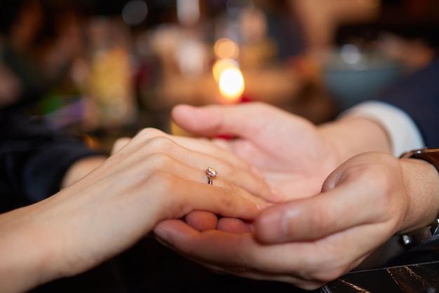 Young man putting ring on finger of his fiancee after marriage proposal closeup