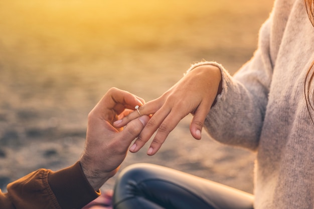 Photo young man putting wedding ring on woman finger