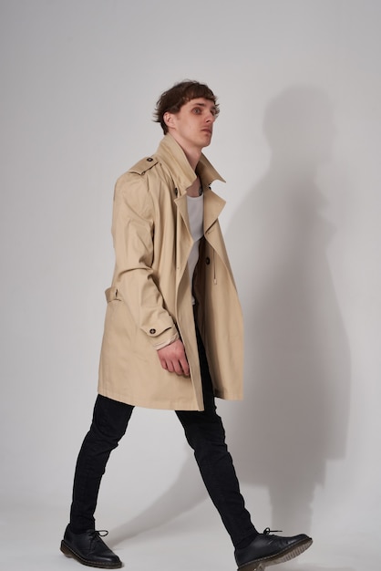 Young man in a raincoat in the studio on a light background hipster guy with trendy hairstyle