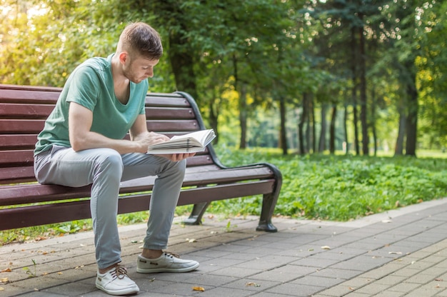 公園で本を読んでいる若い男