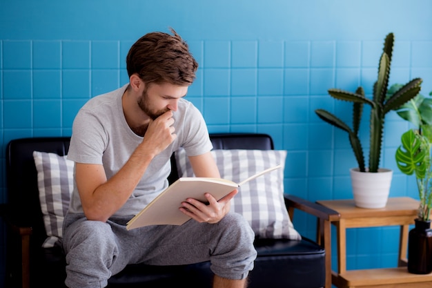 リビングルームのソファーで読書をしている若い男