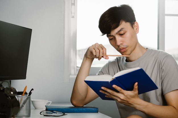 Young man reading book while at home