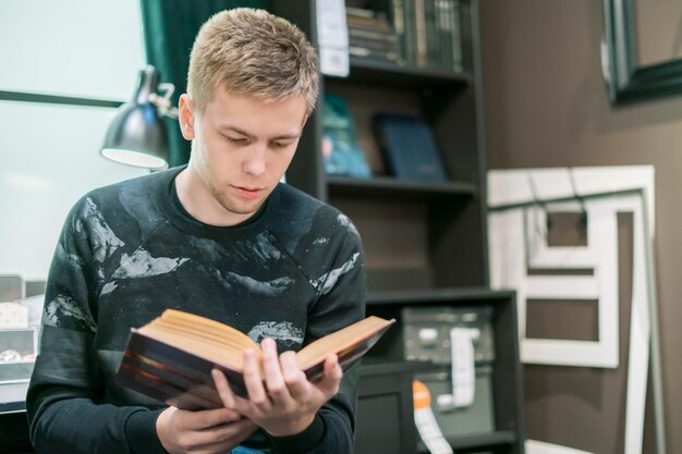 Photo young man reading a science book in the workshop place