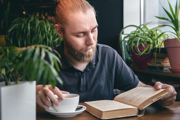 若い男がカフェでお茶を飲みながら本を読む