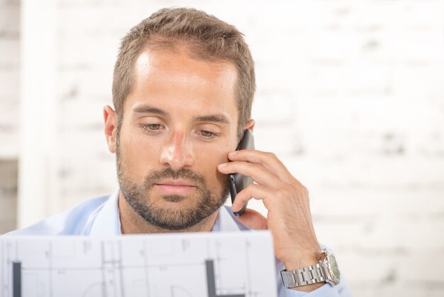 A young man reads a plan and phone