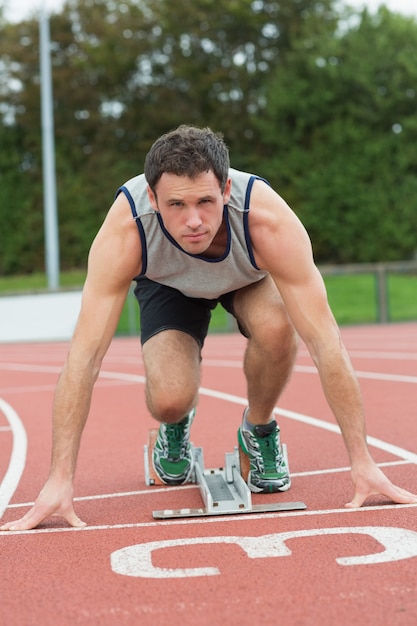 走っているトラックでレースする準備ができている若い男