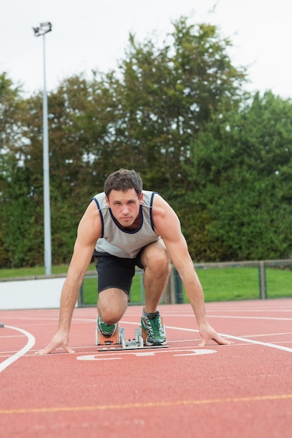 走っているトラックでレースする準備ができている若い男