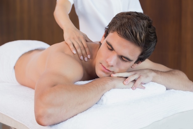 Young man receiving shoulder massage at spa center