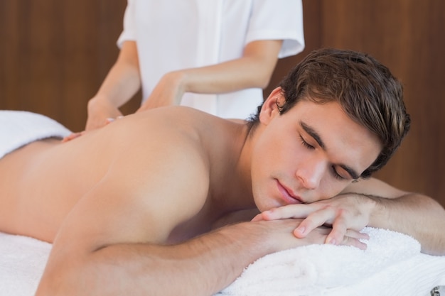 Young man receiving shoulder massage at spa center