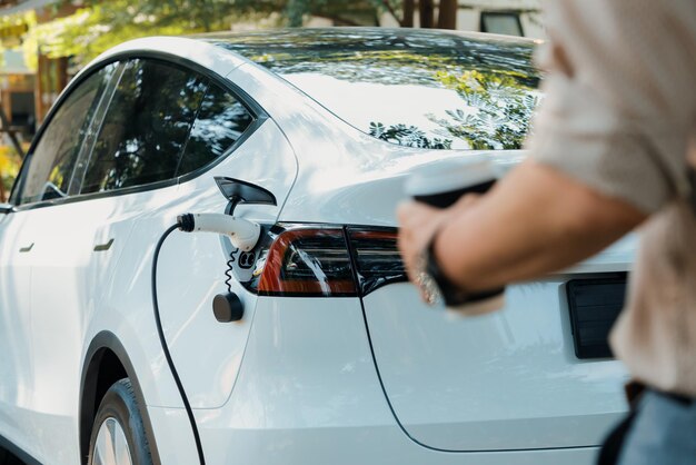 Foto giovane ricarica la batteria delle auto elettriche dalla stazione di ricarica