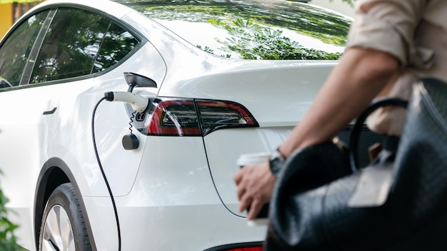 Young man recharge electric cars battery from charging station expedient