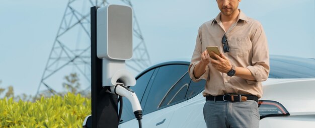 Young man recharge EV car battery at charging station Expedient