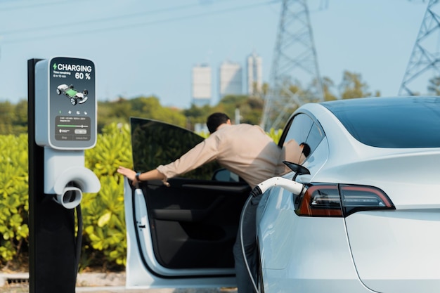 Young man recharge EV car battery at charging station Expedient