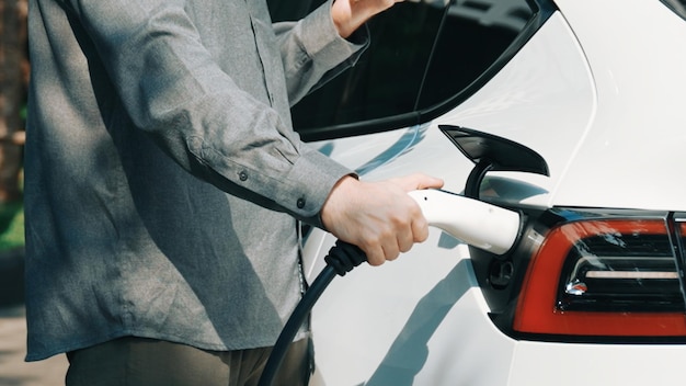 Young man recharge ev electric car battery at condo innards