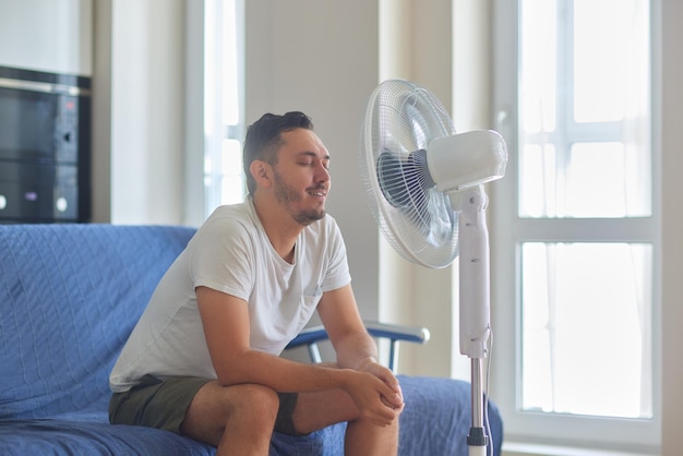 Foto giovane che si rilassa sotto il ventilatore dell'aria a casa