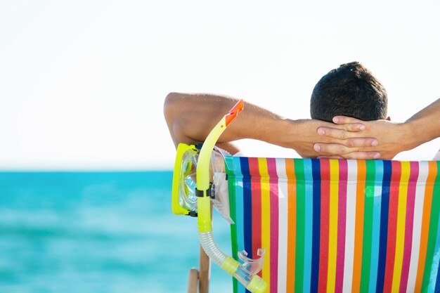 Young man relaxing on beach near blue water