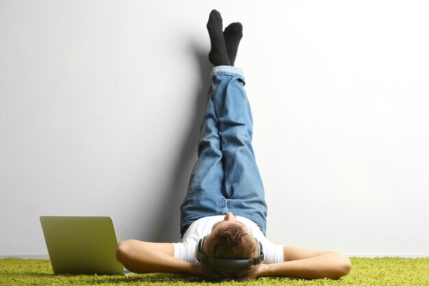 Young man relaxing on carpet and listening to music