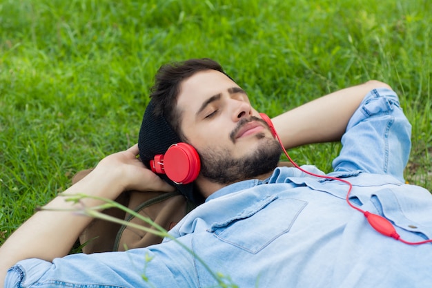 リラックスして、芝生の上の音楽を聴く若い男。