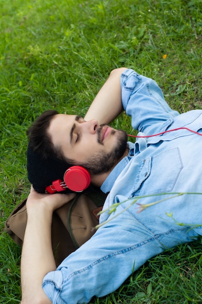 リラックスして、芝生の上の音楽を聴く若い男。