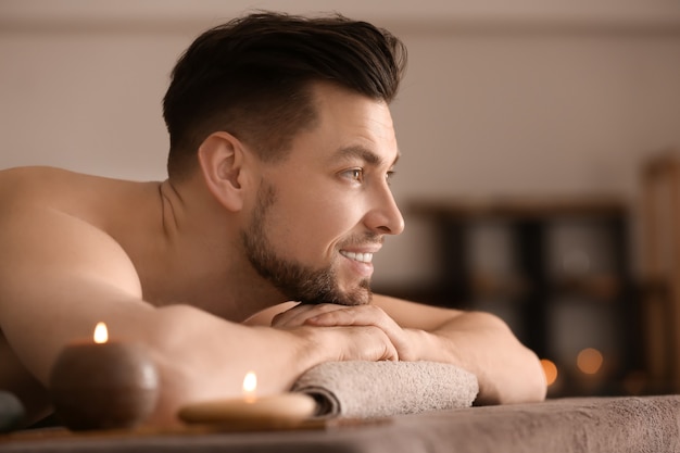 Photo young man relaxing on massage table in spa salon