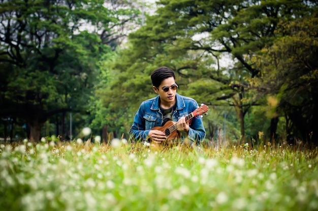 Young man relaxing in the park with his ukulele