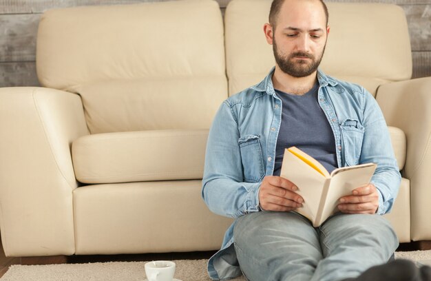 Photo young man relaxing reading book in living room.