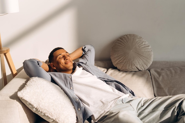 Photo young man relaxing on sofa enjoying sunlight in living room
