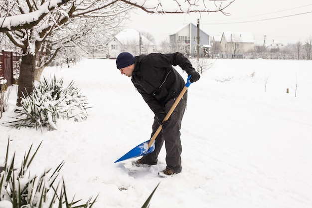 Young man remove snow near the suburban house