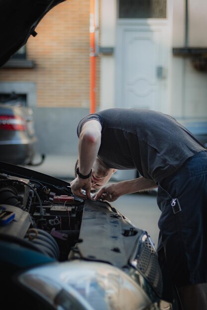 A young man removes the protective partition in the hood of a car