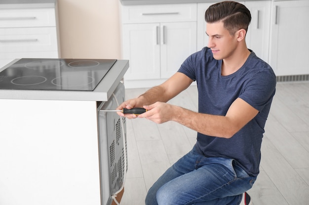 Young man repairing oven in kitchen