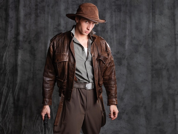 Photo a young man in retro style an adventure character the hero of the adventure a guy in a hat and a lea