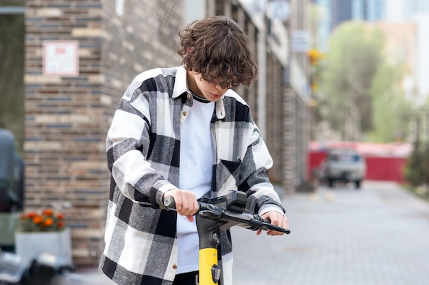 Young man rides an electric scooter looking at the application on a smartphone