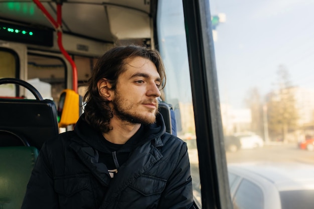 A young man rides in a trolleybus and looks out the window