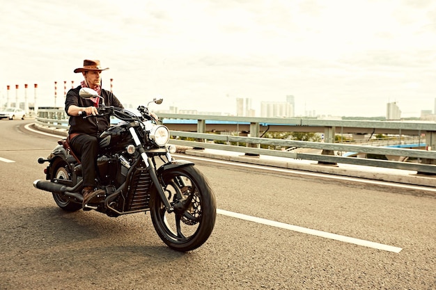 Young man riding big bike ,motorcycle on city road against urban and town building scene. Motion blur